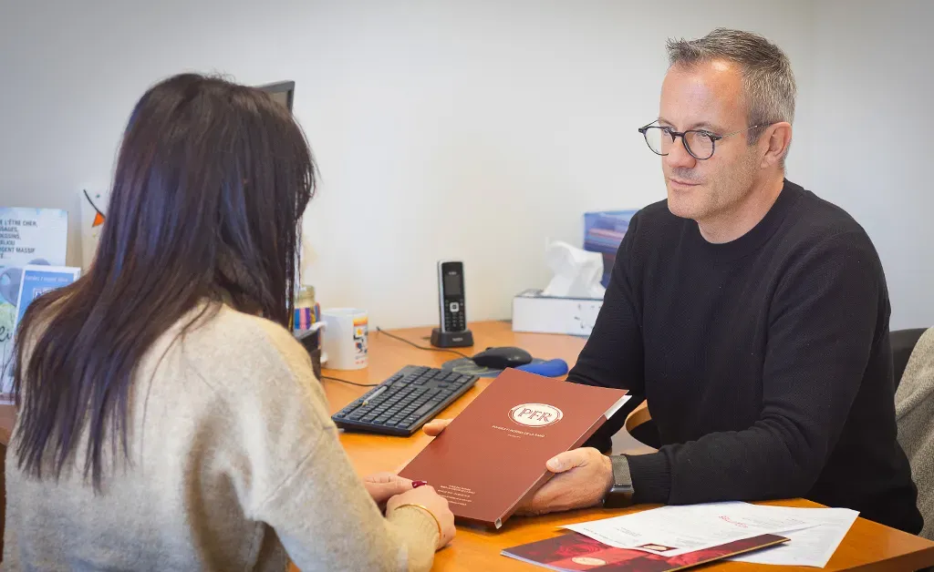 Conseiller en pompes funèbres remettant une brochure d'information à une cliente bureau.